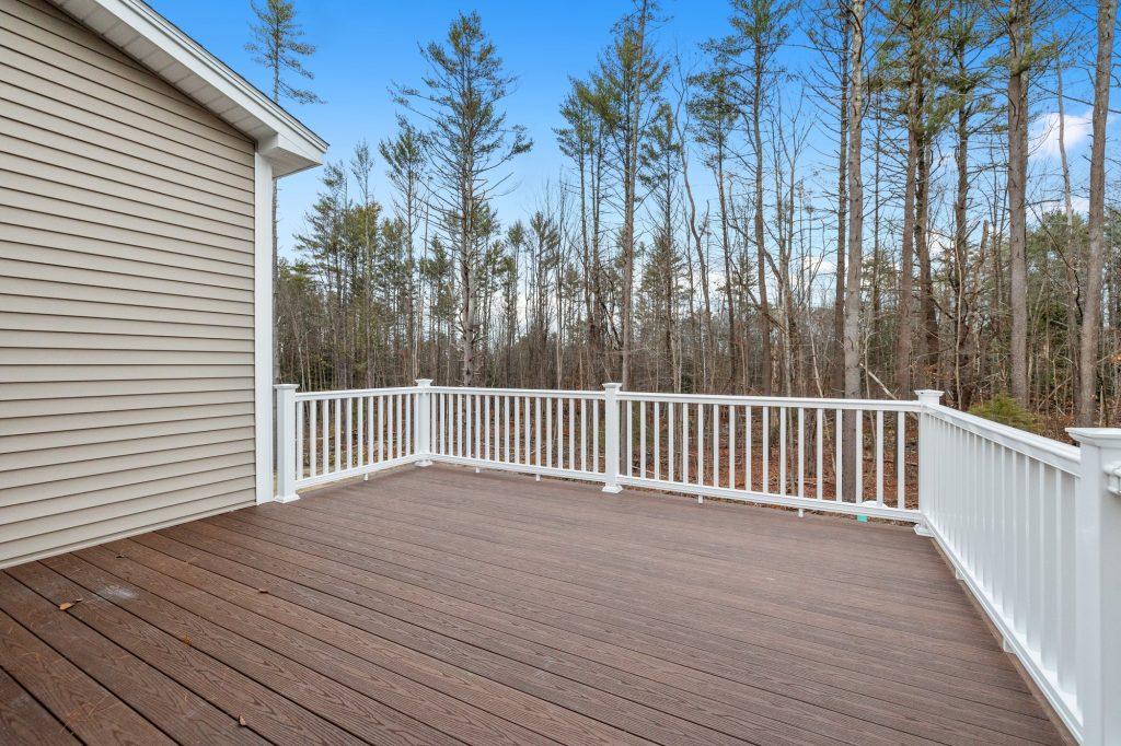 Decking boards of a porch with white railings in a suburb house with shutters
